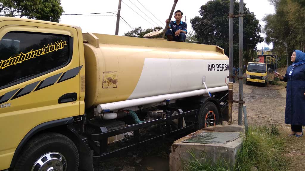 Petugas, Disaksikan Manajer Junior Humas dann Kesekretariatan PDAM Tirta Raharja, Sri Hartati Memantau Alur Pengisian Air Bersih ke dalam Truk Tanki