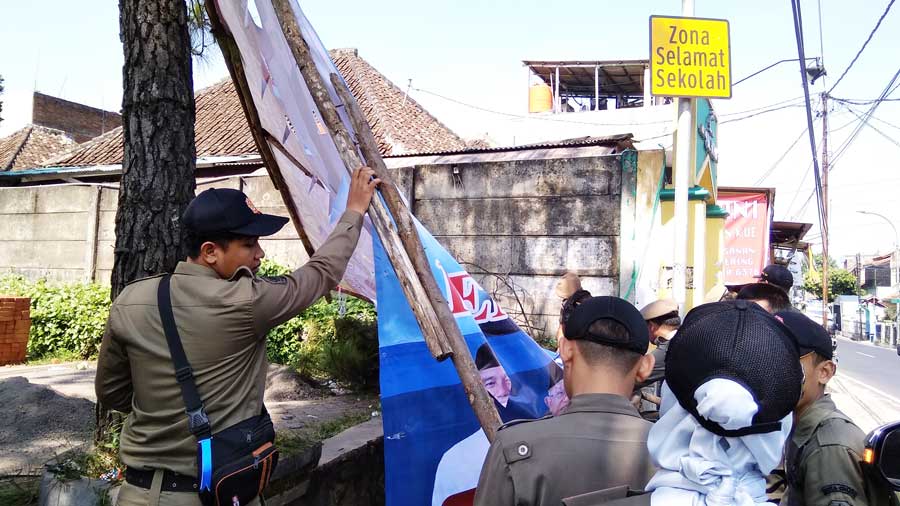 Satpol PP Kota Cimahi menertibkan baliho klaim kemenangan pasangan Prabowo-Sandiaga Uno yang terpasang