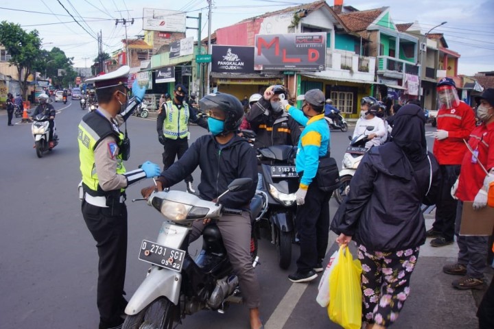 Petugas kepolisian Saat cek suhu badan sejumlah pengendara motor Persimpangan Jalan Jati Cihanjuang