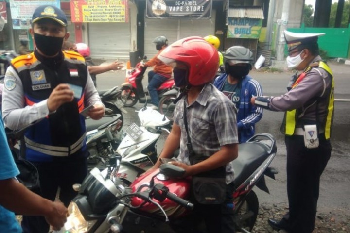 Petugas melakukan pemeriksaan pengendara sepeda motor di check point saat PSBB