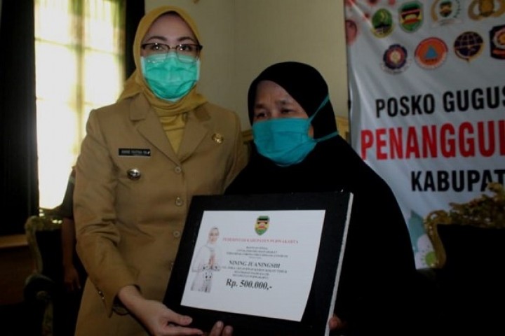 Bupati Purwakarta Anne Ratna Mustika menyerahkan secara simbolis bantuan tunai kepada salah seorang warga.