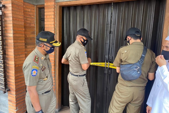 satpol pp saat memasang garis line sebuah rumah makan yang diduga pemilik nya terpapar virus covid-19.