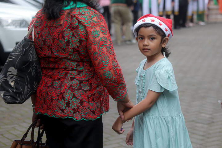 Salah seorang anak dituntun  ibunya saat akan mengikuti ibadah pagi Natal  bersama keluarganya, Kamis, 25 Desember 2025. 
