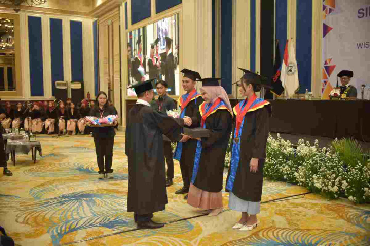 Ketua Stikom Bandung Dr Dedy Jamaludin Malik, M.Si menyerahkan penghargaan kepada lulusan terbaik pada Wisuda Gelombang X di Hotel Papandayan, Sabtu (14/2/2026).  